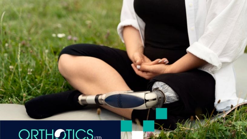 An amputee wearing a prosthetic sitting on the grass